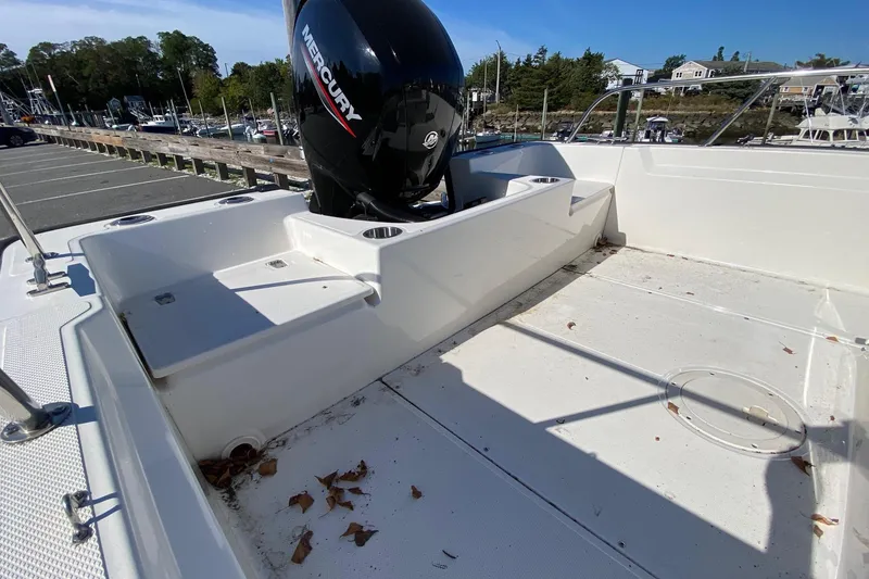 Slide: The Image of 2023 Boston Whaler 190 Montauk boat deck with Mercury engine, parked outdoors. - 8