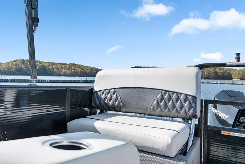 Slide: The Image of 2021 Crest Classic DLX 220 SLRC boat interior with cushioned seating and scenic lake view. - 16