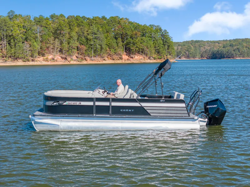 Slide: The Image of 2021 Crest Classic DLX 220 SLRC pontoon boat on a scenic lake. - 2