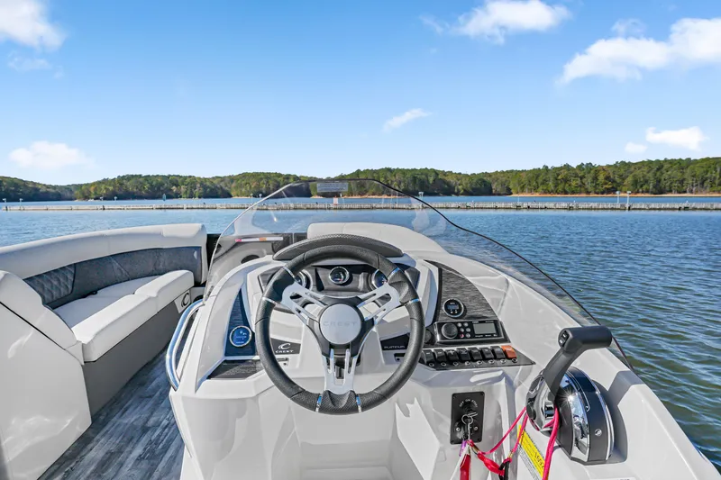 Slide: The Image of Crest Classic DLX 220 SLRC 2021 boat interior with steering wheel on a scenic lake. - 22