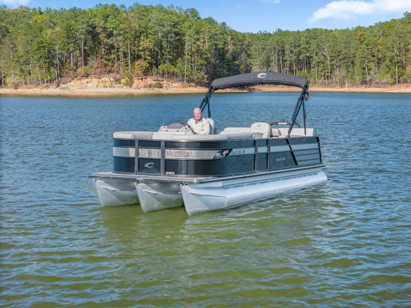 Slide: The Image of 2021 Crest Classic DLX 220 SLRC pontoon boat on a serene lake. - 7