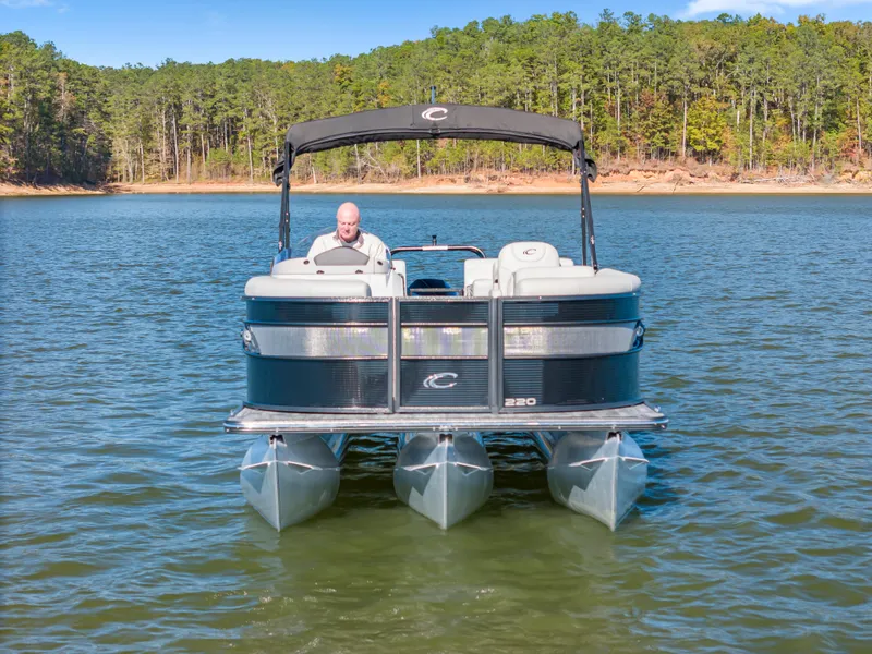 Slide: The Image of 2021 Crest Classic DLX 220 SLRC pontoon boat on a serene lake. - 8