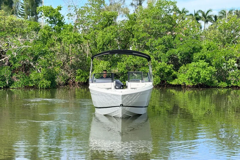 Slide: The Image of 2026 Cobalt R6 Outboard boat cruising on a serene, tree-lined waterway. - 2