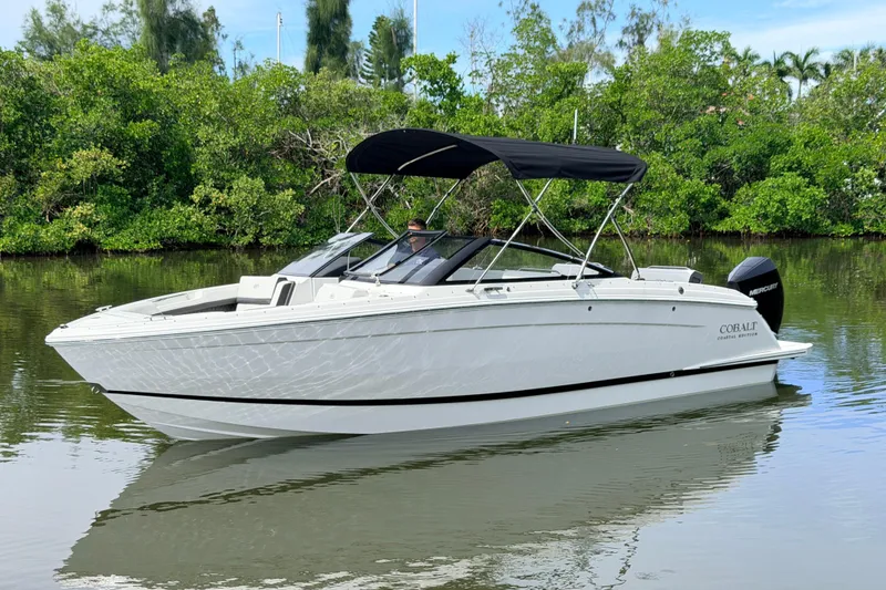 Slide: The Image of 2026 Cobalt R6 Outboard boat on calm water with lush greenery background. - 4