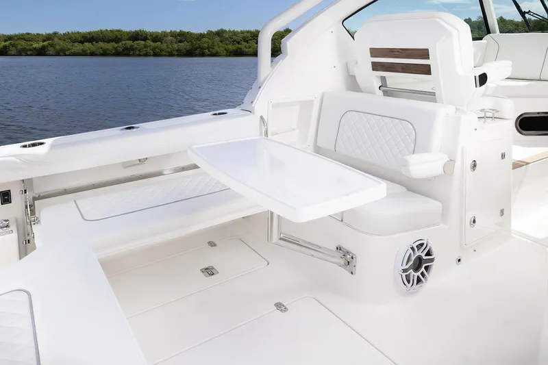 Slide: The Image of Manufacturer Provided Image: 2025 Pursuit DC 326 Dual Console boat interior with seating and table, on calm water. - 11