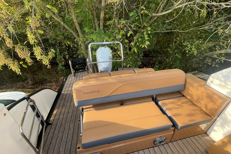 Slide: The Image of 2026 Harris Grand Mariner 230 SLDH boat with tan seating, docked near lush greenery. - 19