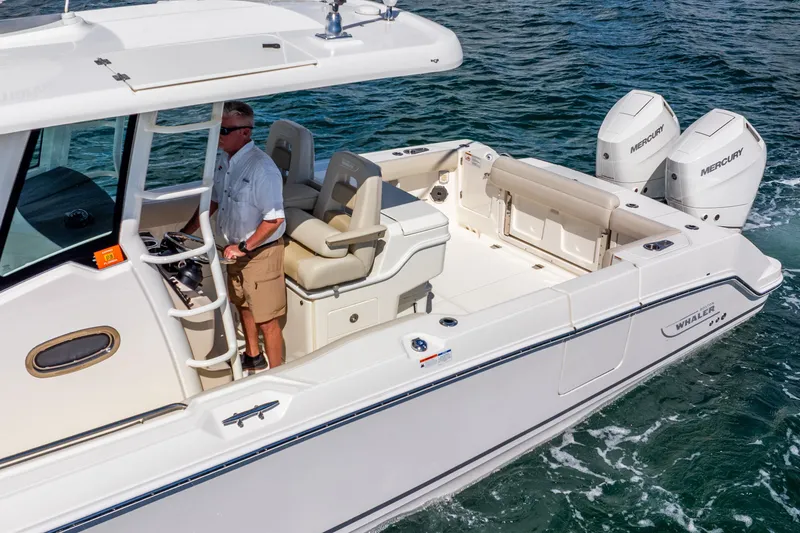 Slide: The Image of 2022 Boston Whaler 330 Outrage boat on water, featuring dual Mercury engines. - 10