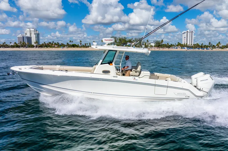 Slide: The Image of 2022 Boston Whaler 330 Outrage cruising on ocean near city skyline. - 14