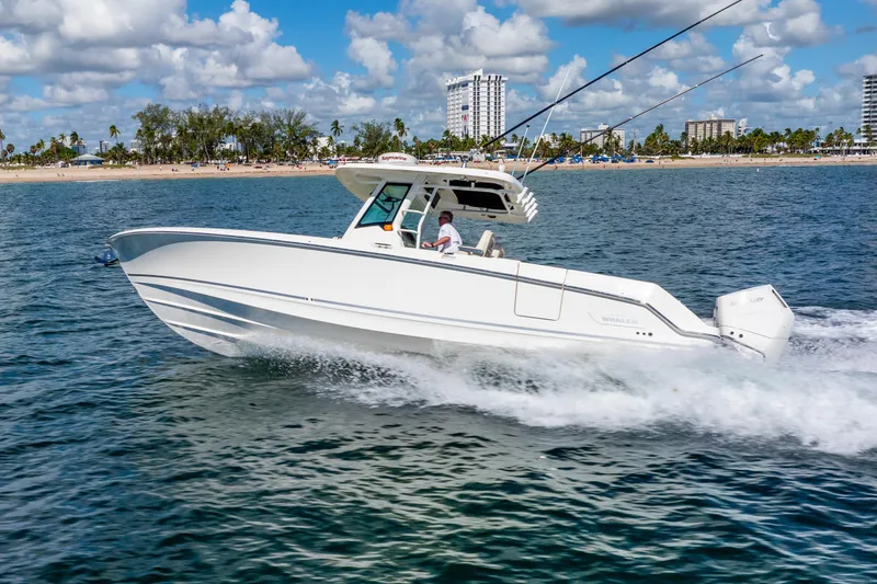 Slide: The Image of 2022 Boston Whaler 330 Outrage cruising on the ocean near a sandy beach. - 15