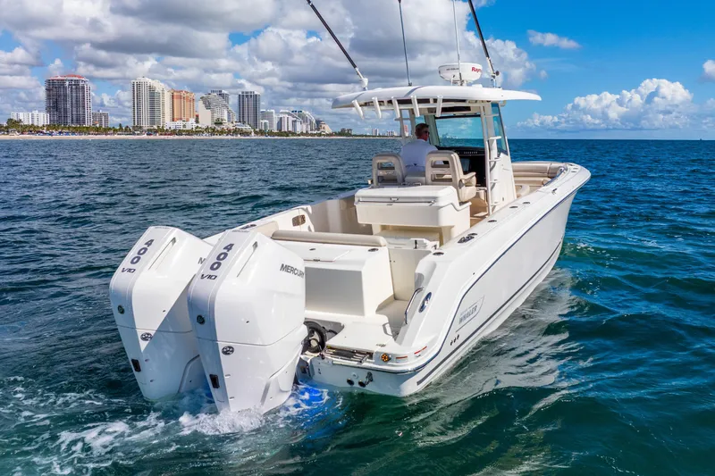 Slide: The Image of 2022 Boston Whaler 330 Outrage boat cruising on ocean near city skyline. - 2