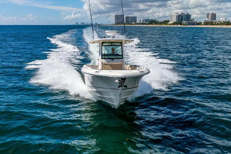 Slide: The Image of 2022 Boston Whaler 330 Outrage cruising on open water near city skyline. - 20