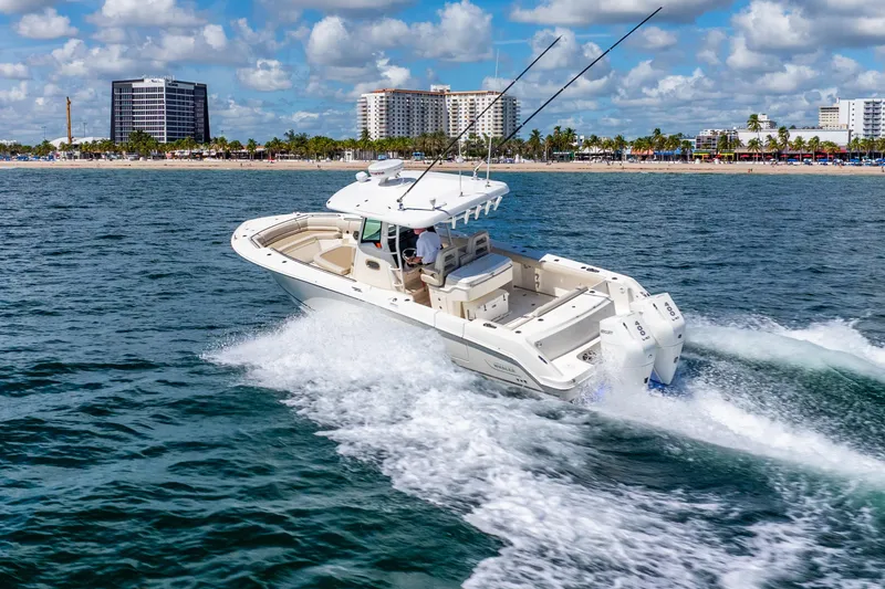 Slide: The Image of 2022 Boston Whaler 330 Outrage cruising near a coastal city skyline. - 22