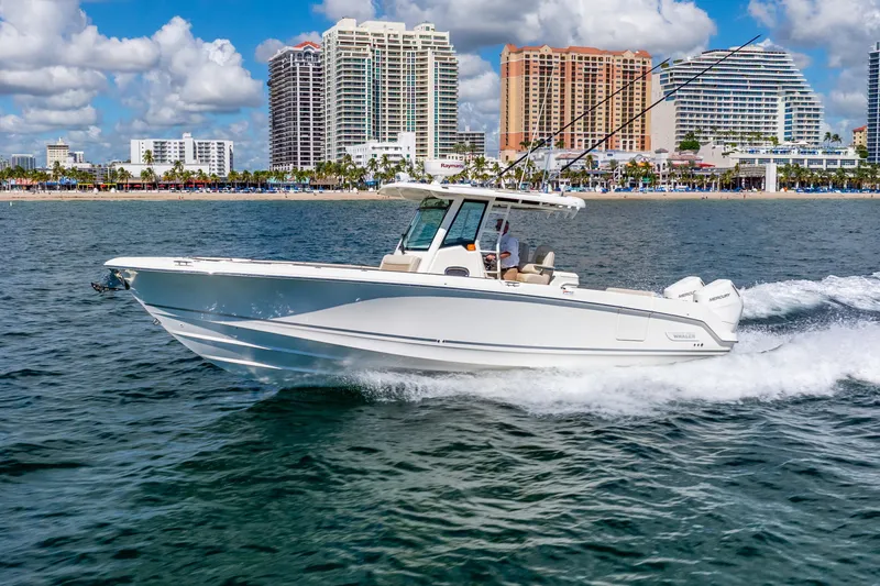 Slide: The Image of 2022 Boston Whaler 330 Outrage cruising near city skyline on a sunny day. - 23