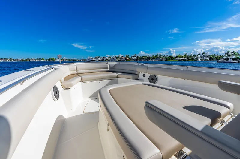 Slide: The Image of 2022 Boston Whaler 330 Outrage boat interior with luxurious seating, blue sky, and waterfront view. - 26