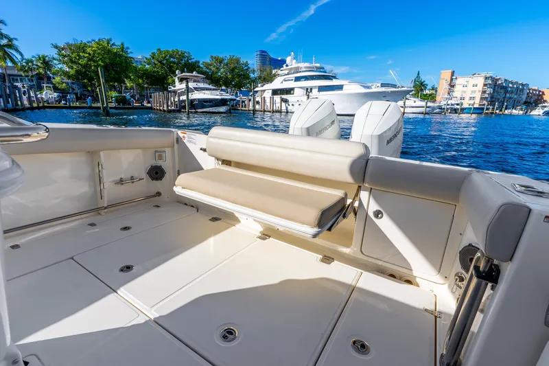 Slide: The Image of 2022 Boston Whaler 330 Outrage boat interior with seating, docked by waterfront. - 36