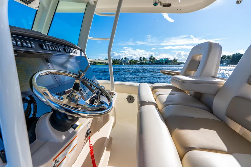 Slide: The Image of 2022 Boston Whaler 330 Outrage interior with steering wheel, luxurious seating, and ocean view. - 38
