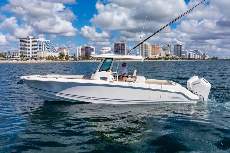 Slide: The Image of 2022 Boston Whaler 330 Outrage boat cruising near a city skyline on a sunny day. - 5