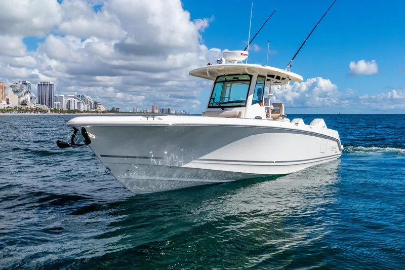 Slide: The Image of 2022 Boston Whaler 330 Outrage cruising on ocean near city skyline under blue sky. - 7