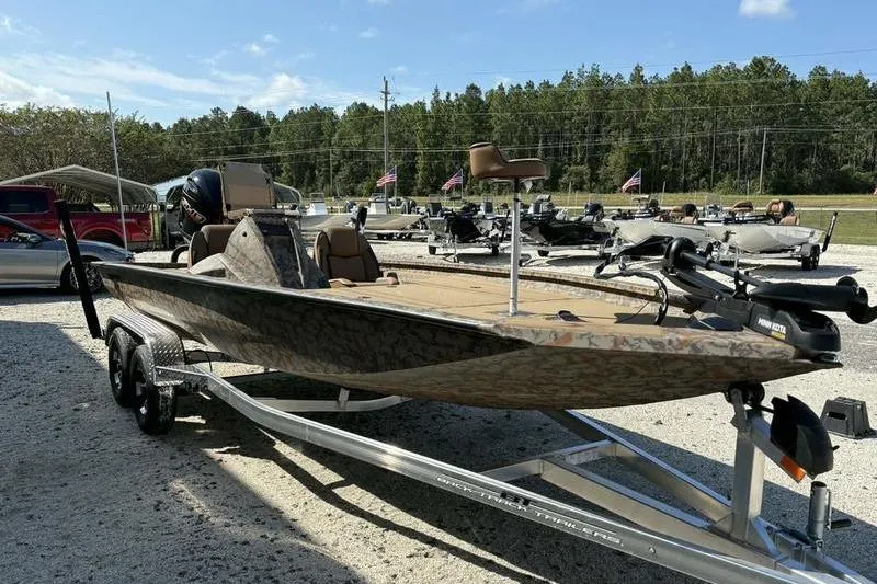 Slide: The Image of 2026 Xpress H20 Bass boat on trailer, parked outdoors, surrounded by trees and vehicles. - 12