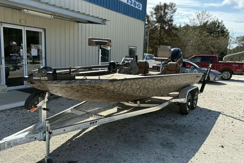 Slide: The Image of 2026 Xpress H20 Bass boat on trailer outside a building, featuring camo design and Minn Kota motor. - 6