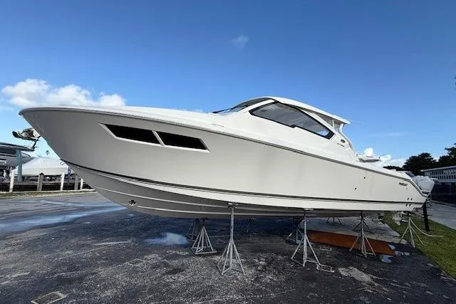 The Image of 2026 Pursuit DC 365 Dual Console boat on display, elevated on stands. - 0