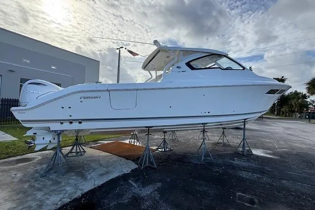 Slide: The Image of 2025 Pursuit DC 365 Dual Console boat on stands, displayed outdoors. - 2