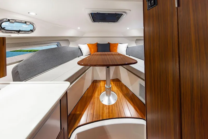Slide: The Image of Manufacturer Provided Image: 2025 Pursuit OS 325 Offshore cabin interior with wood table and cushioned seating. - 19