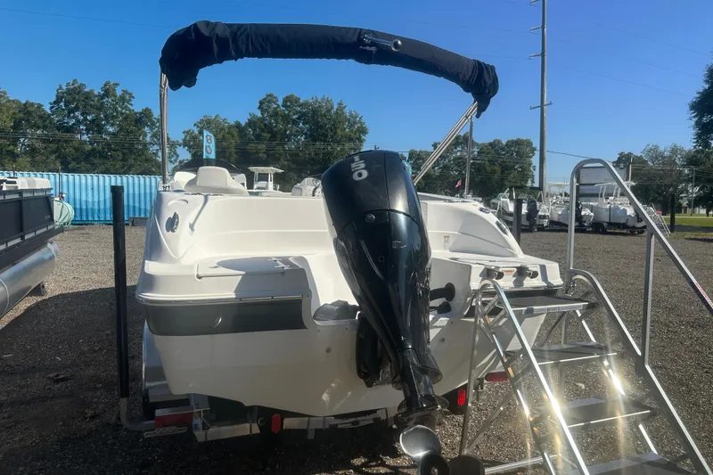 Slide: The Image of 2022 Hurricane Sundeck Sport 218 OB boat with outboard motor and ladder, parked outdoors. - 3