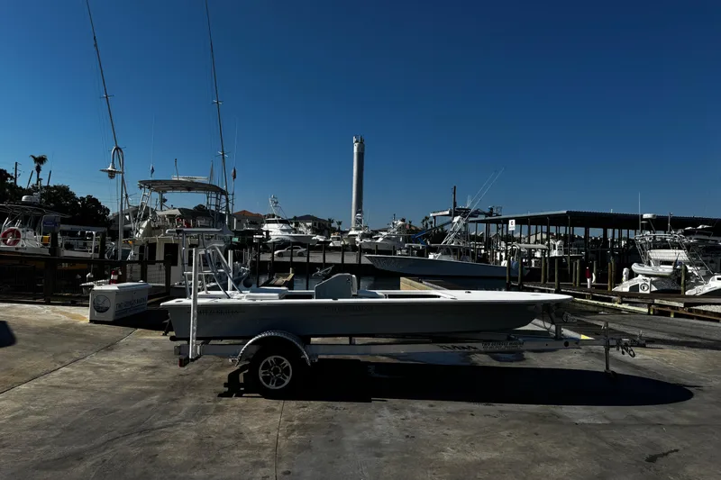 Slide: The Image of 2026 Mitzi Skiffs 17 Tournament boat on trailer at marina, surrounded by various docked boats. - 5