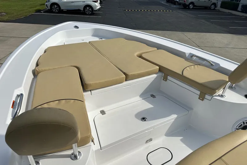 Slide: The Image of 2025 Sportsman Masters 267 Bay Boat with beige cushioned seating in a parking lot. - 9