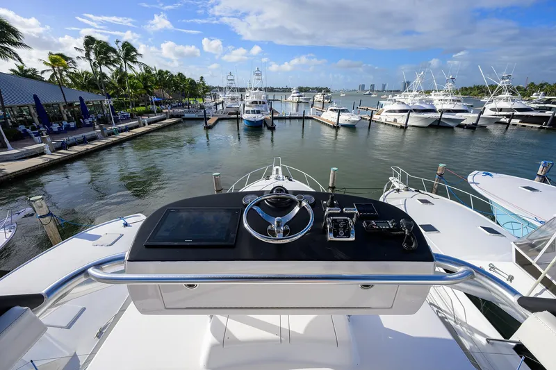 Slide: The Image of 2015 Viking 52 Open yacht at marina, featuring helm controls and scenic waterfront view. - 16