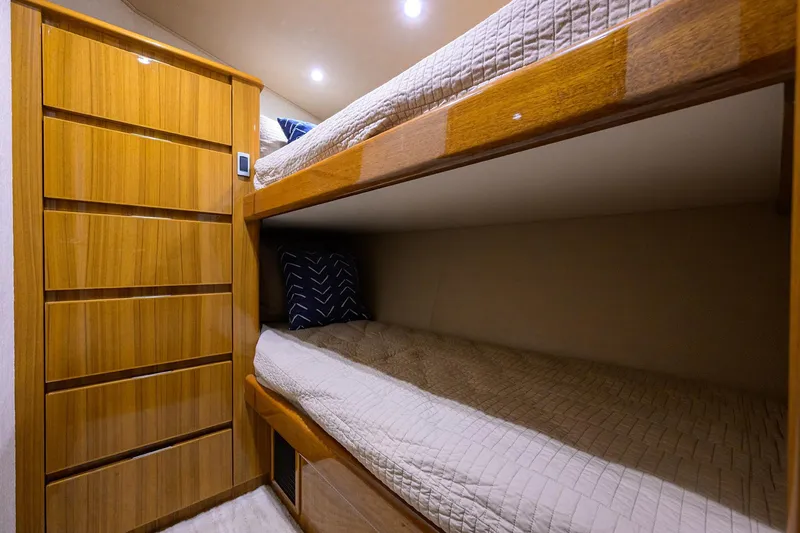 Slide: The Image of Bunk beds in 2015 Viking 52 Open yacht cabin with wooden cabinetry and cozy bedding. - 67