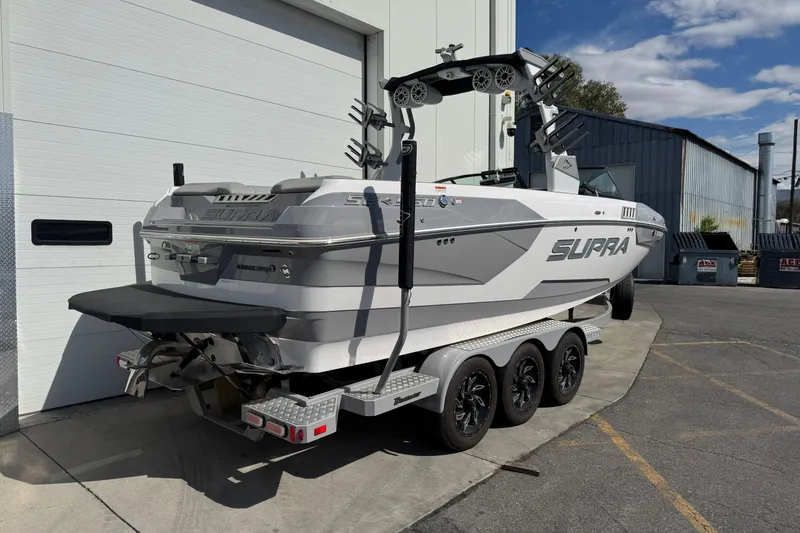Slide: The Image of 2019 Supra SE 575 boat on a trailer, parked outside a building. - 2