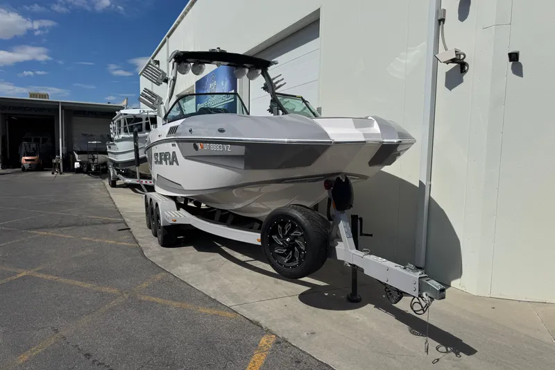 Slide: The Image of 2019 Supra SE 575 boat on trailer outside a warehouse under a clear blue sky. - 4