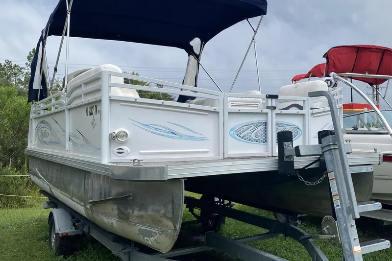The Image of 2010 JC NEPTOON 19 pontoon boat on trailer with canopy, parked on grass. - 1