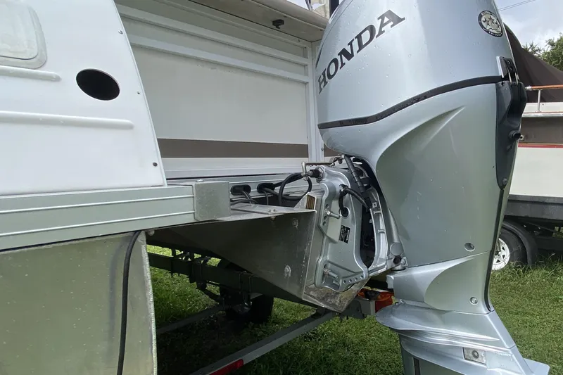 Slide: The Image of 2010 JC NEPTOON 19 boat with Honda outboard motor, parked on grass. - 6