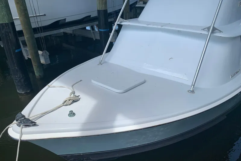 Slide: The Image of 1974 Bertram 31 Flybridge Cruiser boat docked, showing bow with rope and cleat. - 1