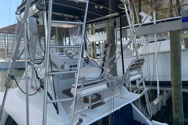 Slide: The Image of 1974 Bertram 31 Flybridge Cruiser with helm and seating, docked in a marina. - 11