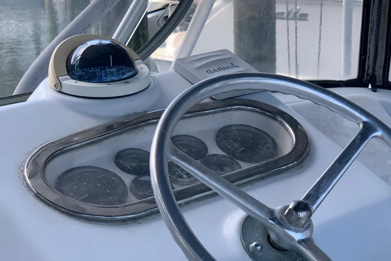 Slide: The Image of 1974 Bertram 31 Flybridge Cruiser helm with compass, Garmin device, and steering wheel. - 13