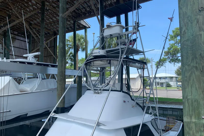 Slide: The Image of 1974 Bertram 31 Flybridge Cruiser docked under a wooden shelter. - 2