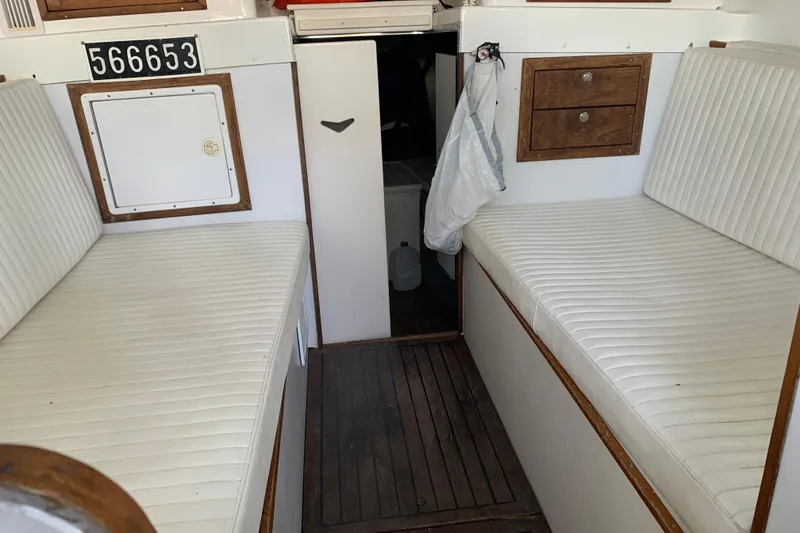 Slide: The Image of 1974 Bertram 31 Flybridge Cruiser interior with white seating and wooden accents. - 43