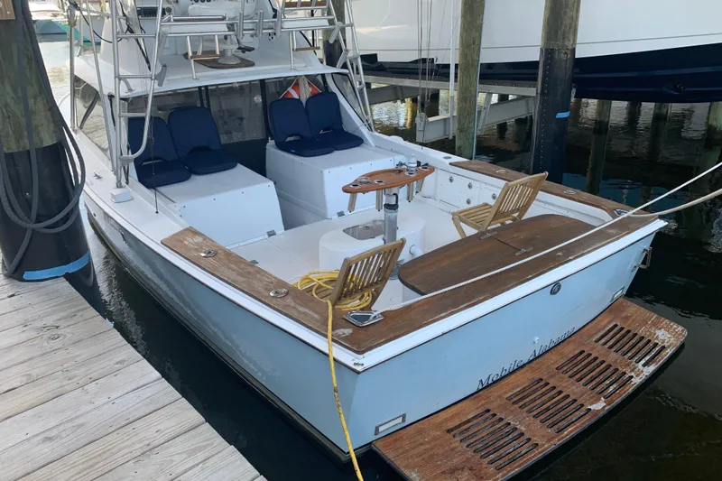 Slide: The Image of 1974 Bertram 31 Flybridge Cruiser docked, featuring wooden deck and seating area. - 5
