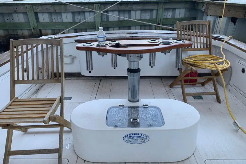 Slide: The Image of 1974 Bertram 31 Flybridge Cruiser deck with chairs, table, and fishing equipment. - 52