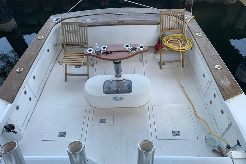 Slide: The Image of 1974 Bertram 31 Flybridge Cruiser deck with chairs, table, and coiled hose. - 7