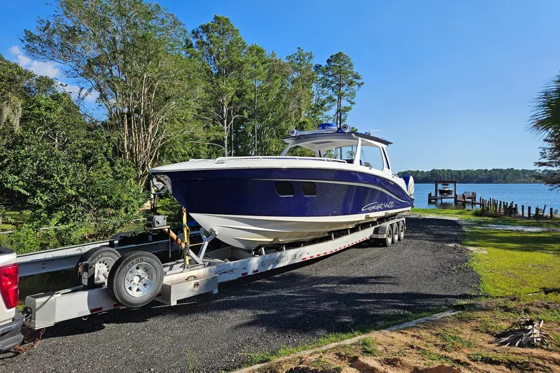 Slide: The Image of 2019 Concept 44' Cuddy Cabin boat on trailer by lakeside, surrounded by trees. - 11