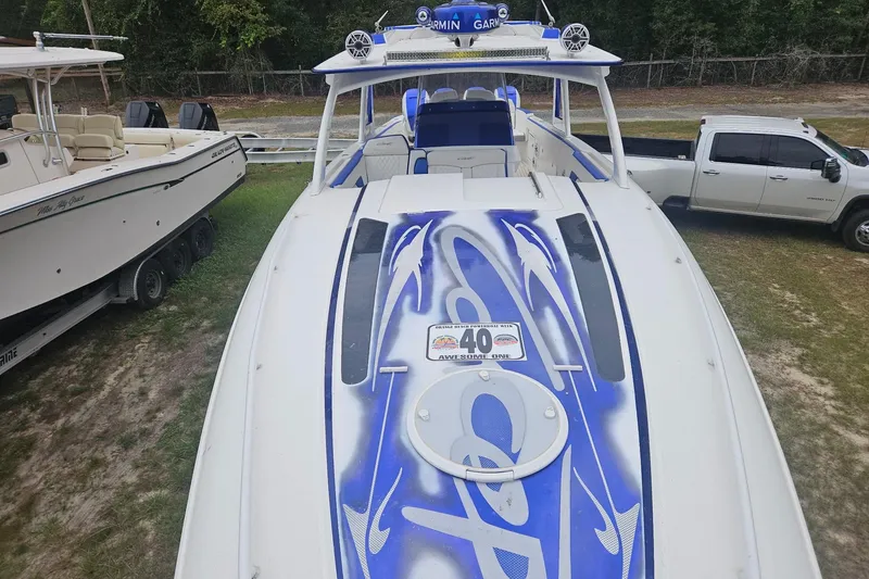 Slide: The Image of 2019 Concept 44' Cuddy Cabin boat with custom blue graphics, parked near a truck. - 16