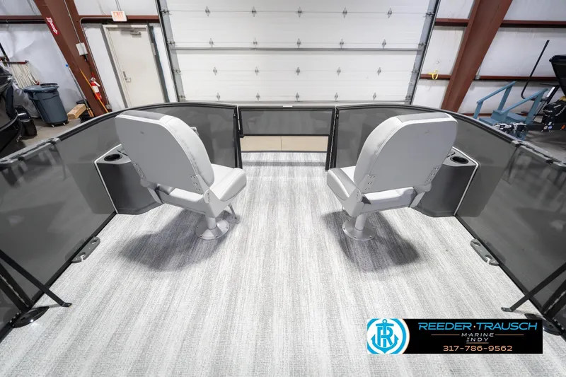 Slide: The Image of 2026 Bennington 22 SF boat interior with two swivel seats and cup holders in a showroom. - 21