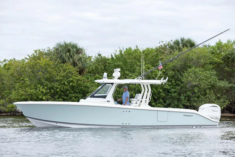 Slide: The Image of Manufacturer Provided Image: 2025 Pursuit S 328 Sport boat cruising near lush greenery. - 2