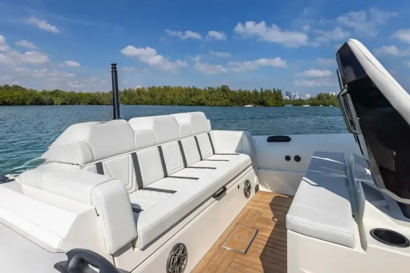 Slide: The Image of 2025 Technohull GTX boat interior with white seating, on a serene lake under blue skies. - 12