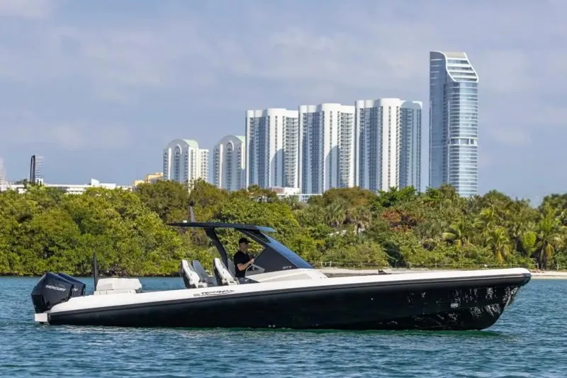 Slide: The Image of 2025 Technohull GTX boat cruising near city skyline and lush greenery. - 6